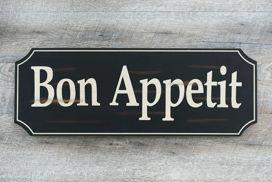 A bon appetit painted sign on wood background.